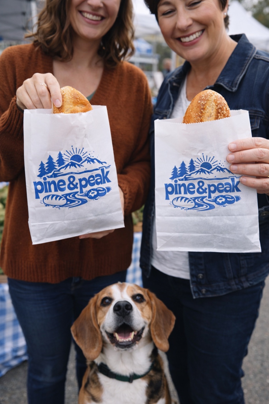Two people holding Pine & Peak paper bags, with a beagle at their feet
