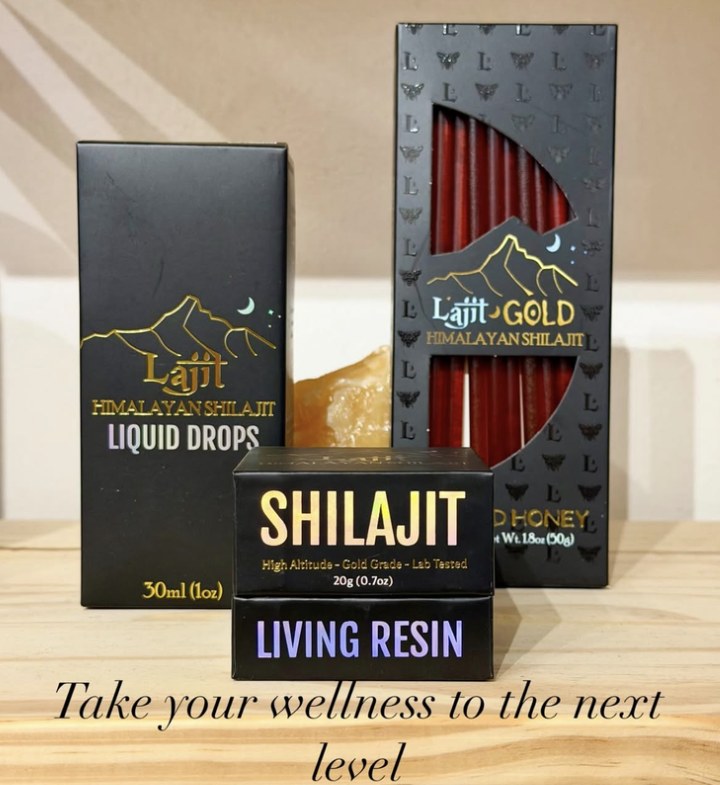 Lajit Gold packaging on a shelf: liquid drops, honey sticks, and a Shilajit living resin box, all black with gold mountain marks